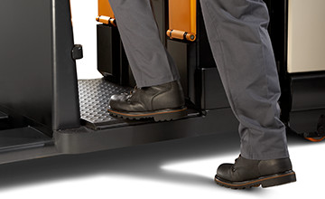 operator stepping onto the PC series pallet truck with operator-sensing floorboard