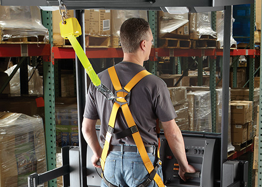 Forklift operator wearing safety harness.