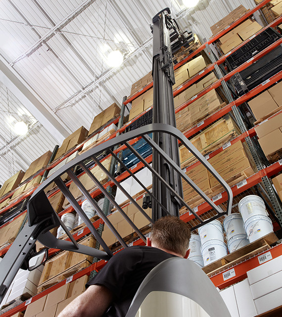 Operator traveling on an RM/RMD Series stand-up reach lift truck